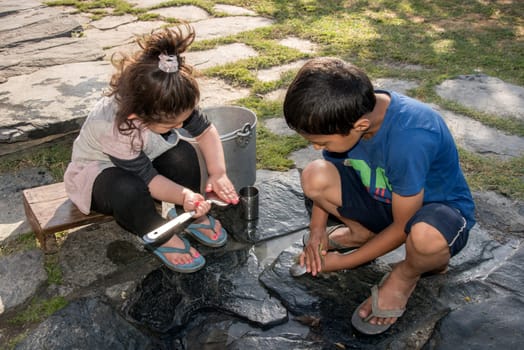 Children cleaning utensils outdoors in Shimla, Himachal Pradesh, India.