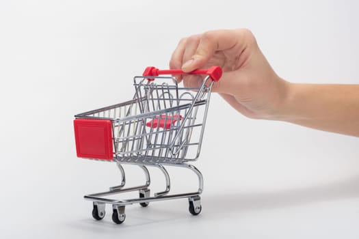 Hand carries empty grocery cart, white background