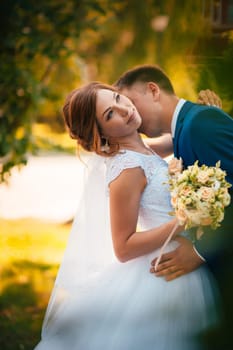 couple groom and bride hugging and kissing on nature park background.
