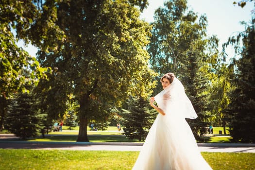 The beautiful brunette bride on a walk in park.