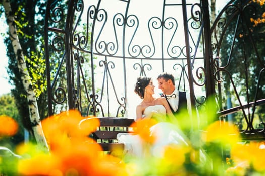 the bride and groom in the gazebo in the park.