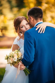 couple groom and bride hugging and kissing on nature park background.