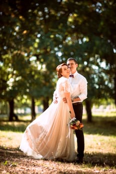 The bride and groom in the background of park trees.