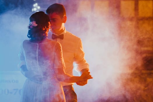 bride and groom dancing the first dance in the blurry background.