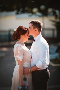 groom and the bride against the trees of the park.