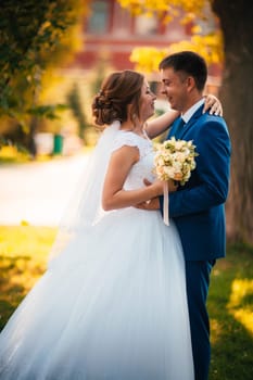 couple groom and bride against the background of orange leaves.