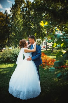 couple groom and bride hugging and kissing on nature park background.
