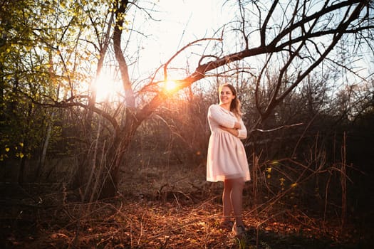 Beautiful girl standing in a field on a sunset background.