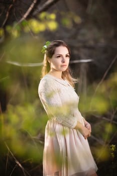 Beautiful girl standing in a field on a sunset background.