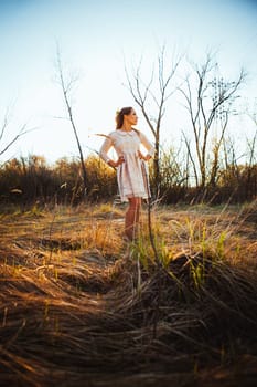 Beautiful girl standing in a field on a sunset background.