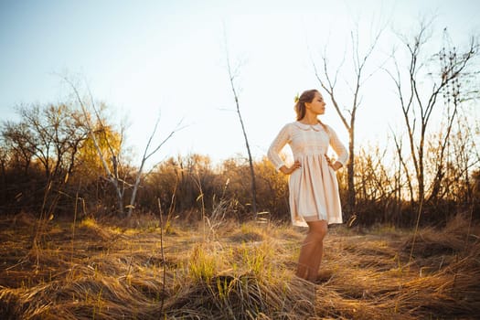 Beautiful girl standing in a field on a sunset background.