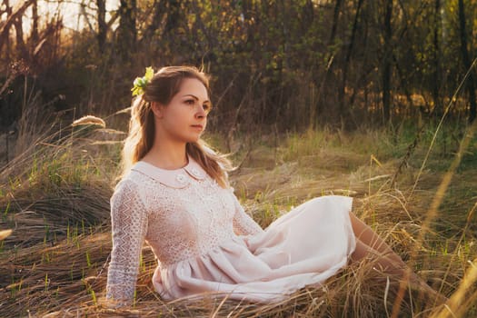 girl is sitting in the field on the sunset background.