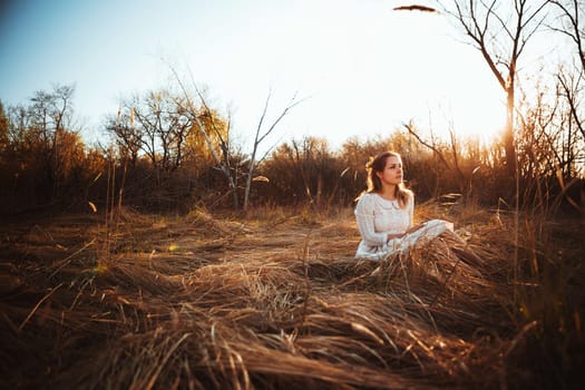 girl is sitting in the field on the sunset background.