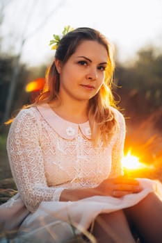 girl is sitting in the field on the sunset background.