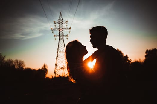 Silhouettes of a guy and girl in a field on a sunset background.