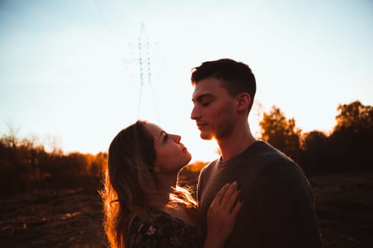 Silhouettes of a guy and girl in a field on a sunset background.