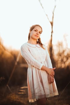 Beautiful girl standing in a field on a sunset background.