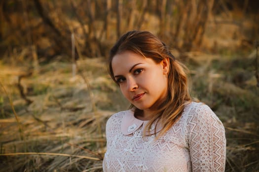 girl is sitting in the field on the sunset background.