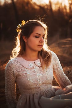 girl is sitting in the field on the sunset background.