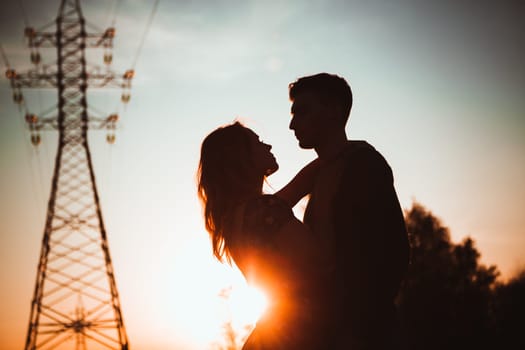 Silhouettes of a guy and girl in a field on a sunset background.
