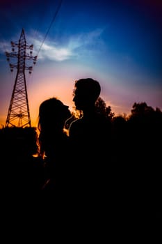 Silhouettes of a guy and girl in a field on a sunset background.