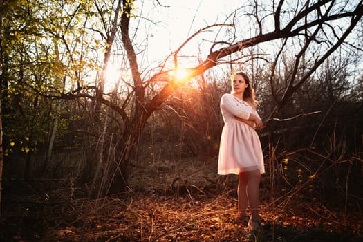 Beautiful girl standing in a field on a sunset background.