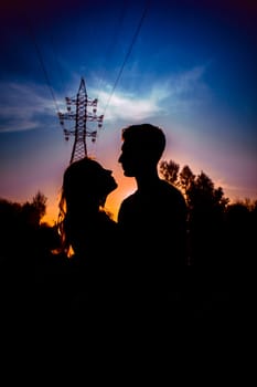 Silhouettes of a guy and girl in a field on a sunset background.