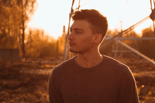 portrait of a guy in the field on a sunset background.