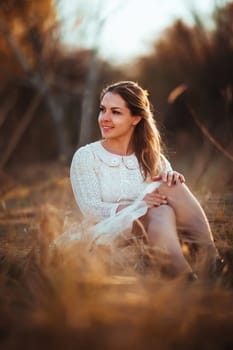 girl is sitting in the field on the sunset background.