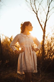 Beautiful girl standing in a field on a sunset background.