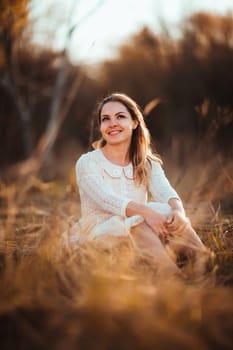 girl is sitting in the field on the sunset background.