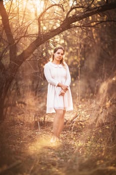 Beautiful girl standing in a field on a sunset background.