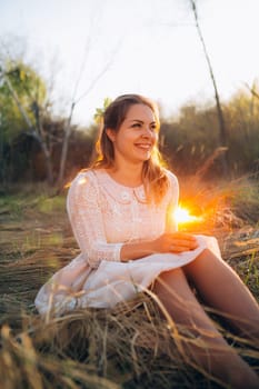 girl is sitting in the field on the sunset background.
