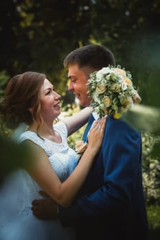 couple groom and bride hugging and kissing on nature park background.