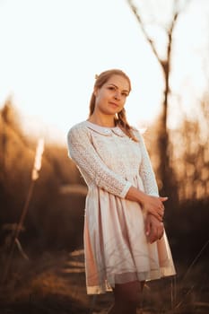 Beautiful girl standing in a field on a sunset background.