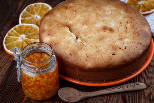 Muffin baked on a wooden table with a jar of candied orange