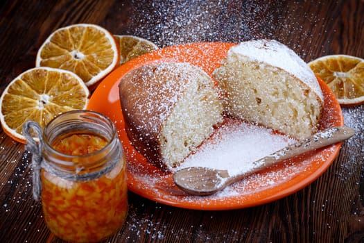 Slices of cake in a plate on a wooden table with a jar of candied orange