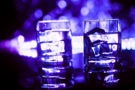 colored lighting of glasses in the night club bar.