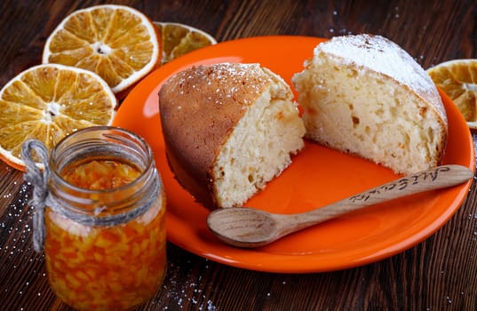 Slices of cake in a plate on a wooden table with a jar of candied orange