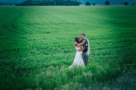 bride and groom stand on the background of the field.