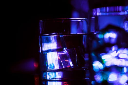 colored lighting of glasses in the night club bar.