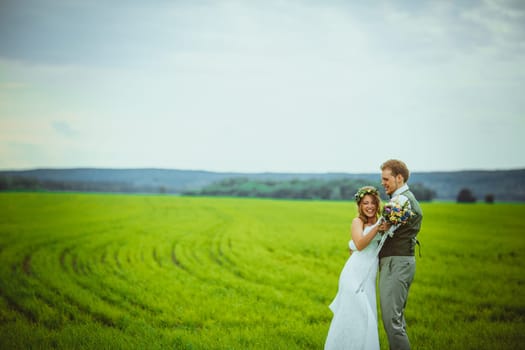 bride and groom stand on the background of the field.