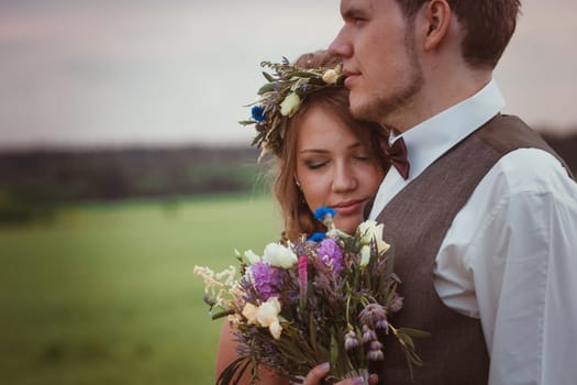 portrait bride and groom stand on the background of the field.