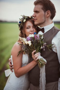 portrait bride and groom stand on the background of the field.