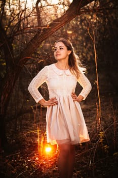 Beautiful girl standing in a field on a sunset background.