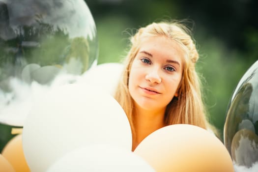portrait of young girl with balloons on nature background.