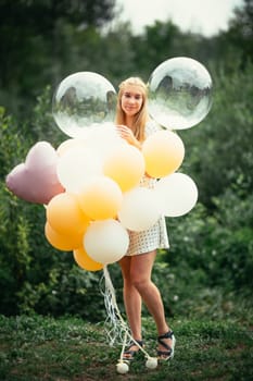 young girl with balloons on nature background.