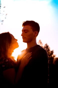 Silhouettes of a guy and girl in a field on a sunset background.