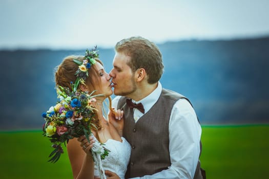 portrait bride and groom stand on the background of the field.