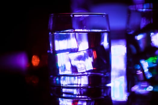 colored lighting of glasses in the night club bar.